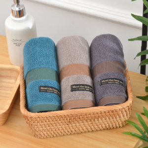 Trois serviettes de bain roulées bleu, beige et gris dans un panier